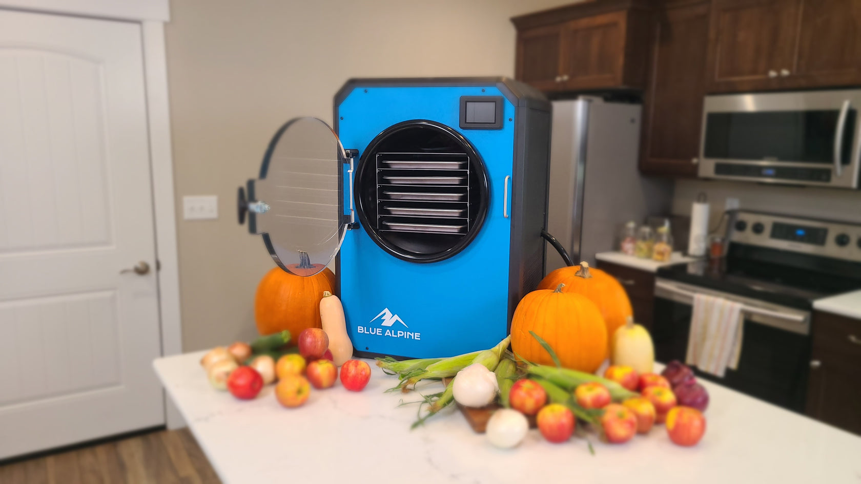 Blue Alpine Freeze Dryer On Table In Kitchen With Pumpkins, Squash, Corn, Apples, Onions, and Zucchini 